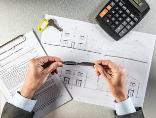 builder hands with key and housing draft thinking about negotiation