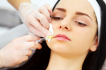 beautician doing beauty injection to woman lips