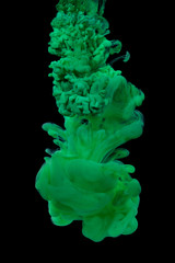 Explosion of green acrylic paint in water on black background.