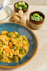 Curry with pork, brussels sprouts and green peas. Blue plate, rice, ginger, green peas.
