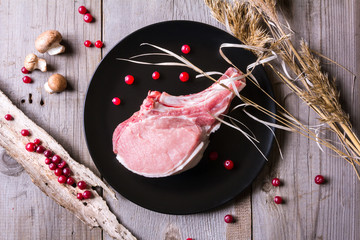 Fresh game meat on black plate and wooden table
