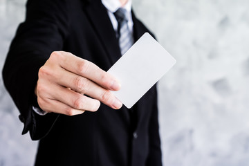 Close up of businessman holding white blank card on grunge background.