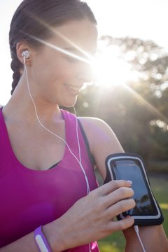 Smiling female jogger listening to music on mobile phone