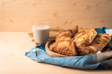 Assortment of pastries with milk on wooden table background.