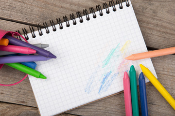 colored crayons and blank page on the wooden table