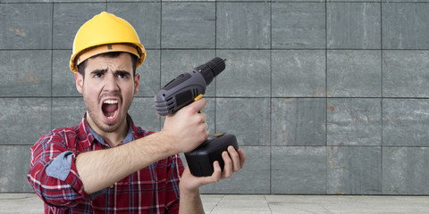 worker with drill screaming rage with the background wall