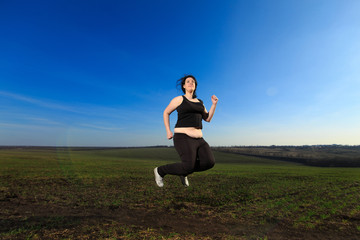 overweight woman jumping in countryside in the meadow