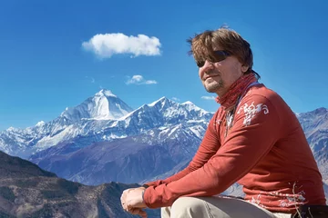 Papier Peint photo Dhaulagiri Male traveler in red shirt sitting and smiling in Himalayas with Dhaulagiri peak at the background