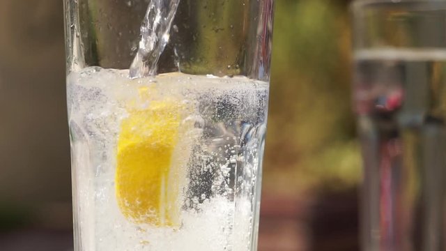 Pouring sparkling water, tonic in a glass beaker. Container filled with sparkling water placed on table. Slow motion full HD video footage 1920x1080