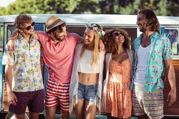 Group of happy friends standing together near campervan