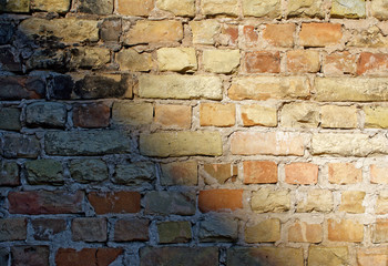Old empty uneven raw varied color brick wall with shadow