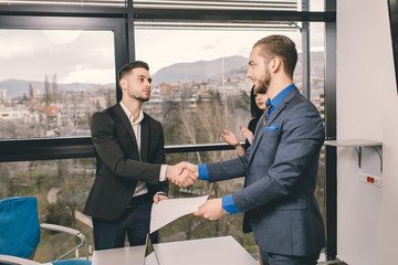 Two men handshaking after signing contract