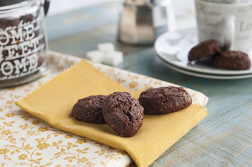 rustic cookies with cocoa and pistachio nuts on decorated tray, cloth napkin and other kitchen items in the background