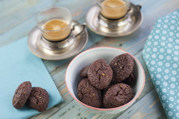 Rustic cookies with chocolate and nuts in ceramic bowl with two cups of espresso and cloth napkins