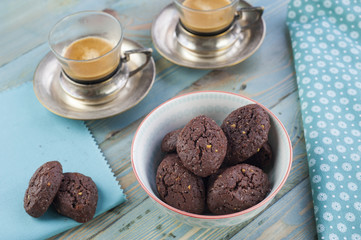 Rustic cookies with chocolate and nuts in ceramic bowl with two cups of espresso and cloth napkins