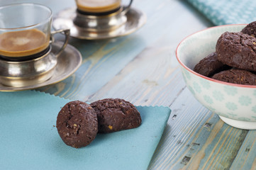 Rustic cookies with chocolate and nuts in ceramic bowl with two cups of espresso and cloth napkins