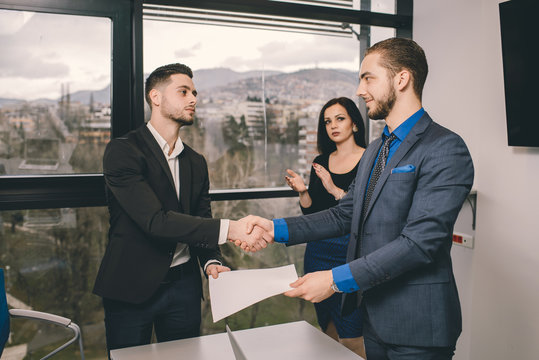 Two men handshaking after signing contract