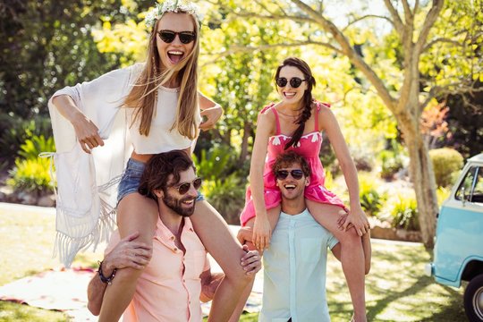 Men Carrying Women On Their Shoulders In Park