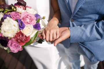 Obraz na płótnie Canvas The man the groom keeps the girl's hand. Colorful bridal bouquet. wedding day, bride accessories