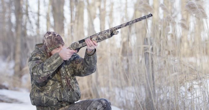 hunter in camo aims and fires shotgun slow motion close up 4k