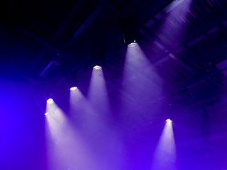 The light rays from the spotlight through the smoke. Lighting equipment on the ceiling. The stage of a theatre or night club. Show or performance.