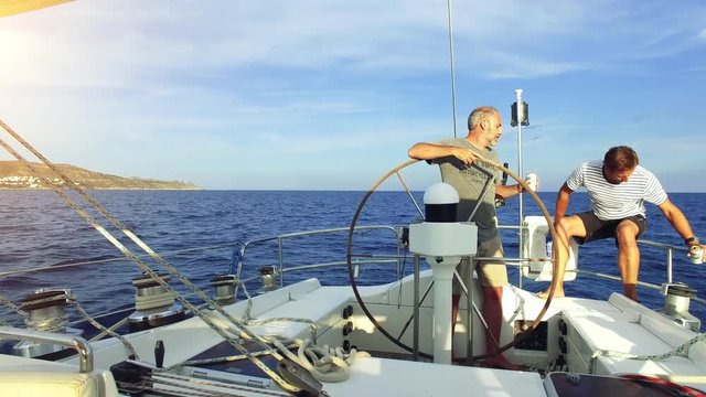 man on steering wheel navigating sail boat