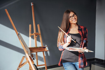 Young woman artist painting a picture in studio