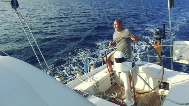 man on steering wheel navigating sail boat