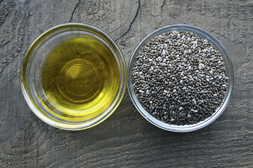 Chia oil with chia seeds in a glass bowls on old wooden background.Organic chia seed oil.Healthy food,superfood or bodycare concept.Selective focus.