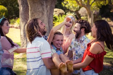 Group of friends lifting woman at campsite