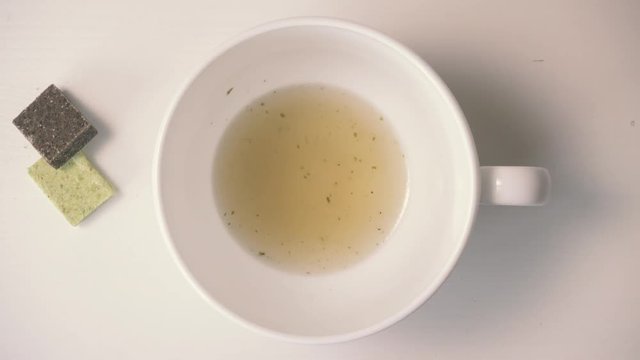 Hot chicken clear soup is poured into the soup ladle in a soup bowl, from bouillon cubes. Top view