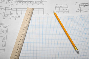 Open blueprints on wooden table background with a pencil and a ruler lying beside.