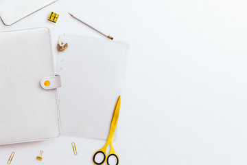 Closed planner with paper inserts, pencil and gold stationery accessories, on a white desk background. Negative space to the right.