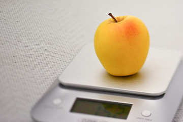 Single golden apple on a kitchen scale