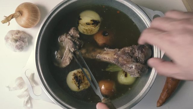 The beef bone in the broth is taken out of the pan with vegetables, top view