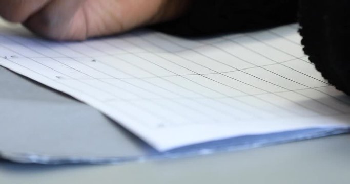 Extreme close up of a young student erasing a word on a gridded paper and then writing another word