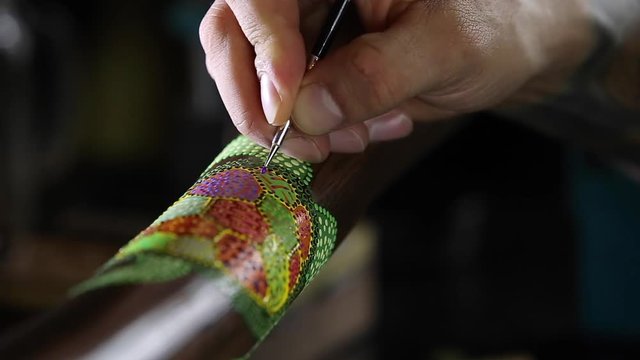 artist paints dots of sea turtle for didgeridoo pointillism panning view