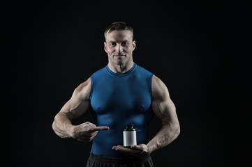 Fototapeta na wymiar handsome bodybuilder man with muscular body holds pill jar, steroids