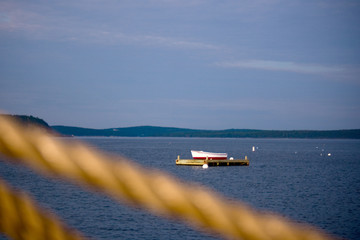 Small Rowboat on Dock in Ocean with Rope in Foreground