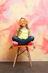 small happy baby girl in orange sunglasses and yellow shirt