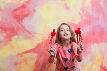 small happy baby girl holding valentines day decorative red hearts