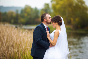 The bride and groom are standing on the bridge.