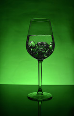 Glass of ice water with a green background