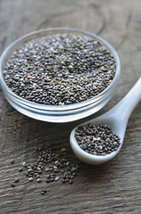 Chia seeds in a white spoon and bowl with chia seeds on old wooden background.Organic chia seeds.Healthy food,superfood or bodycare concept.Selective focus.