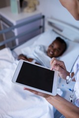 Female doctor using digital tablet during visit in ward