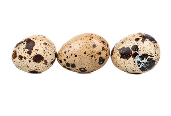 Three raw quail eggs in a row on a white background