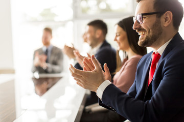 Smiling business group clapping hands at the meeting