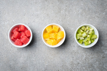 Overhead shot of cut fruits in white bowls