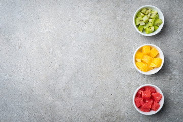Overhead shot of cut fruits in white bowls