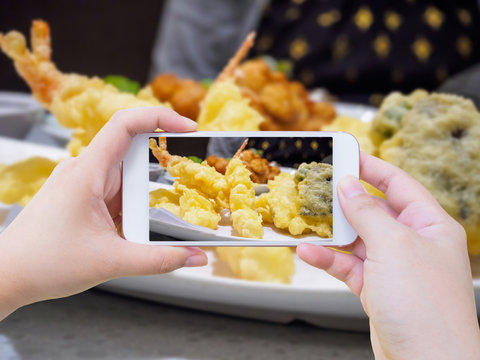 taking photo of shrimp tempura on white plate with smartphone